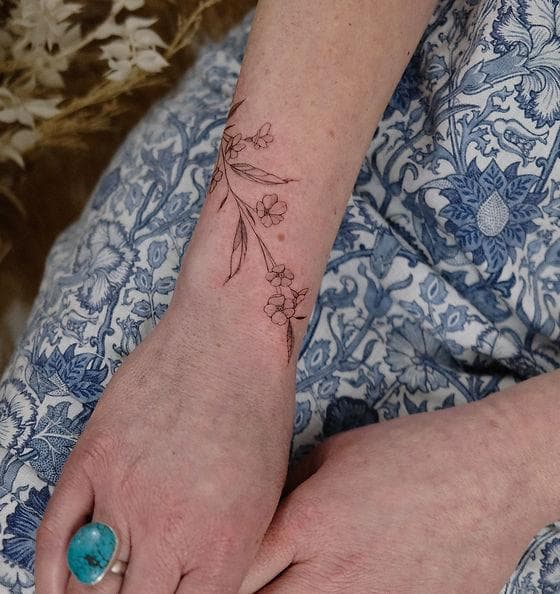 A delicate minimalist fine-line tattoo along the forearm
