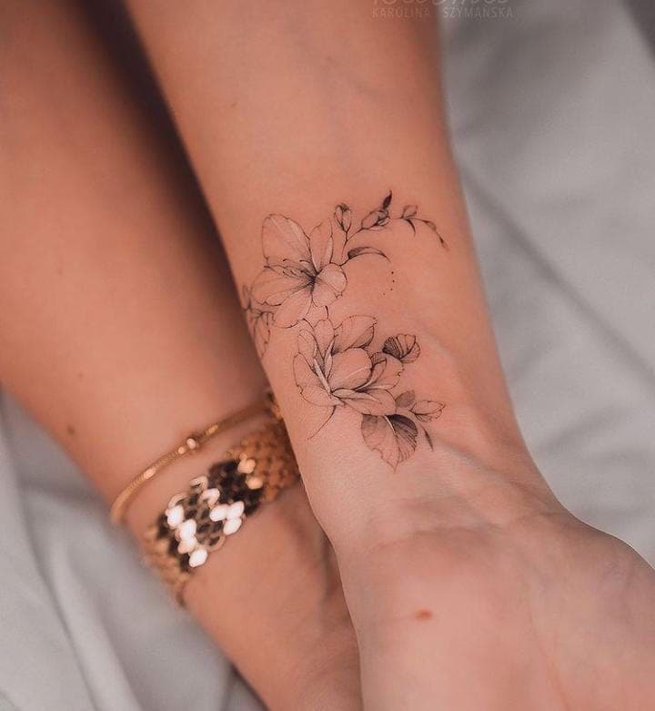 A small fine-line floral tattoo on the wrist